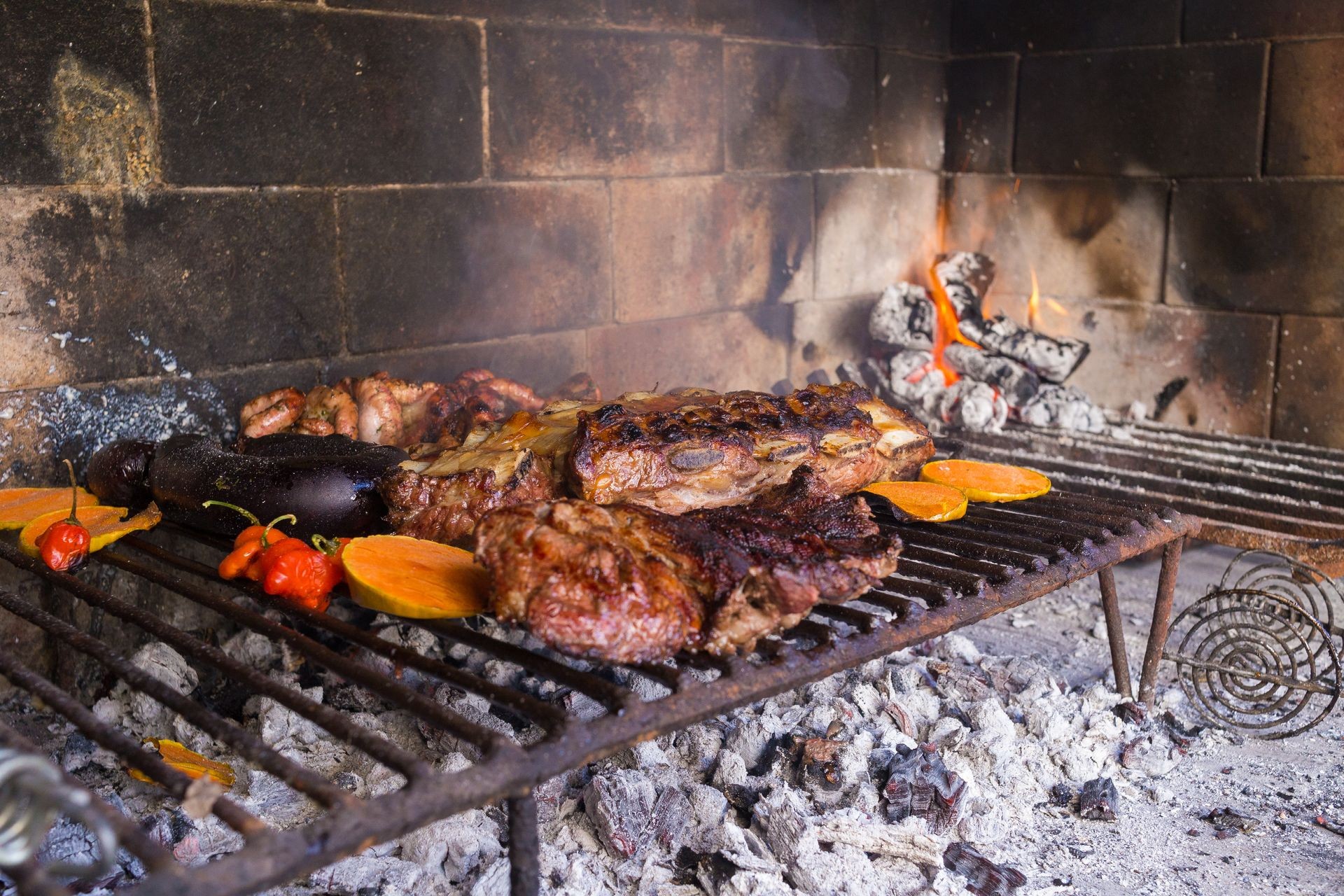 Barbecue for the lunch. Meat cuts and vegetables warming on the embers on an iron grill. Traditional Argentinian bbq.